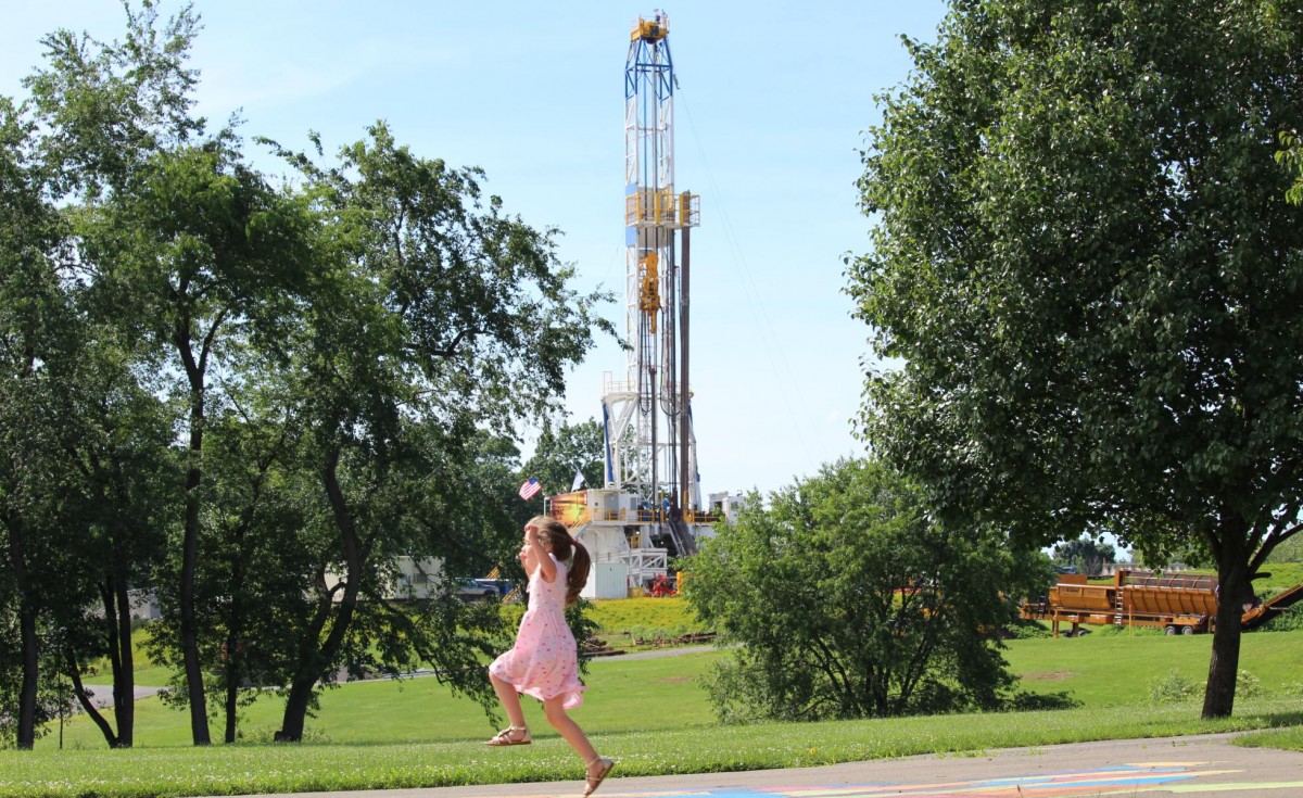 Child playing hopscotch in front of fracking site