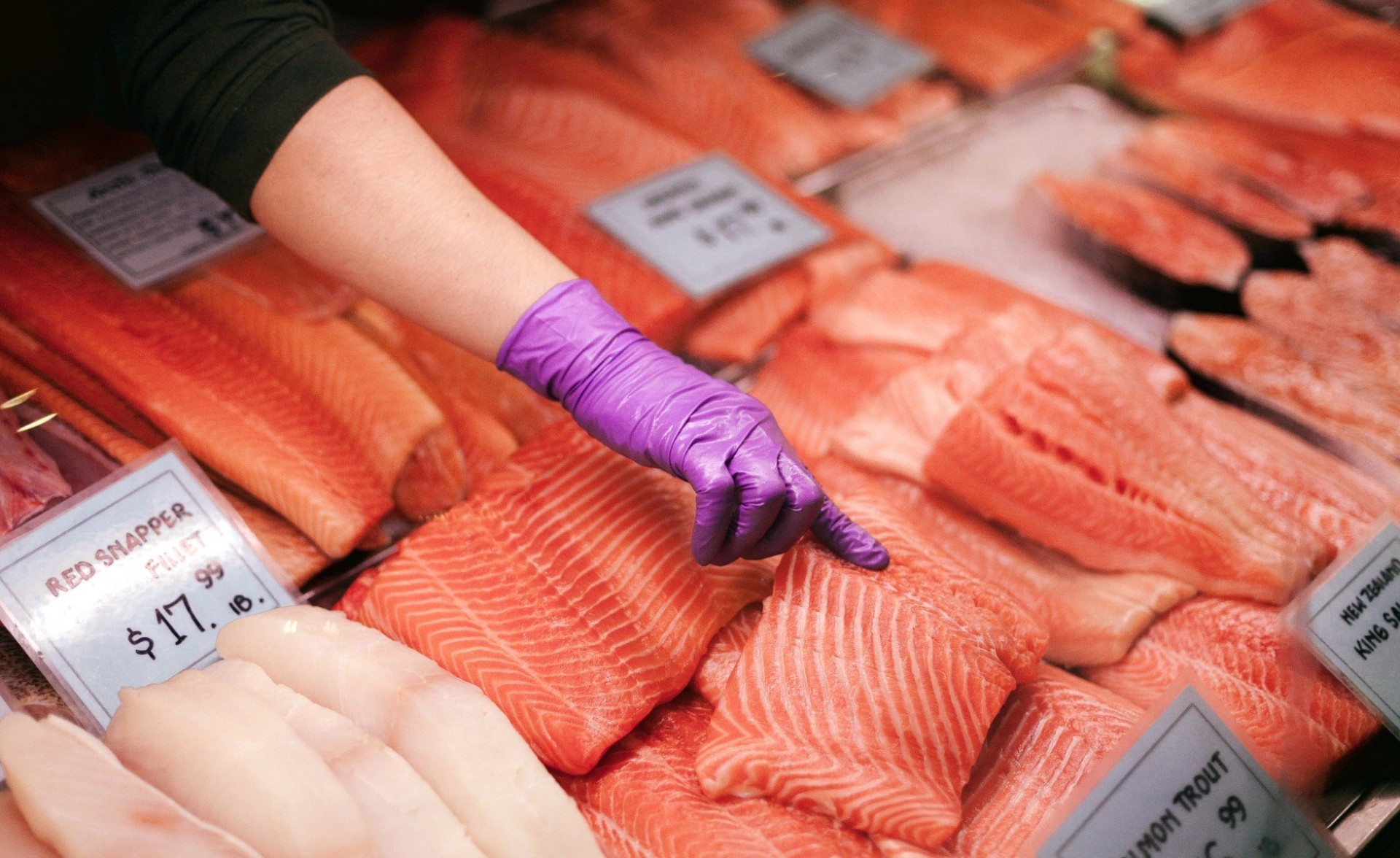 Person pointing at raw salmon at a seafood market