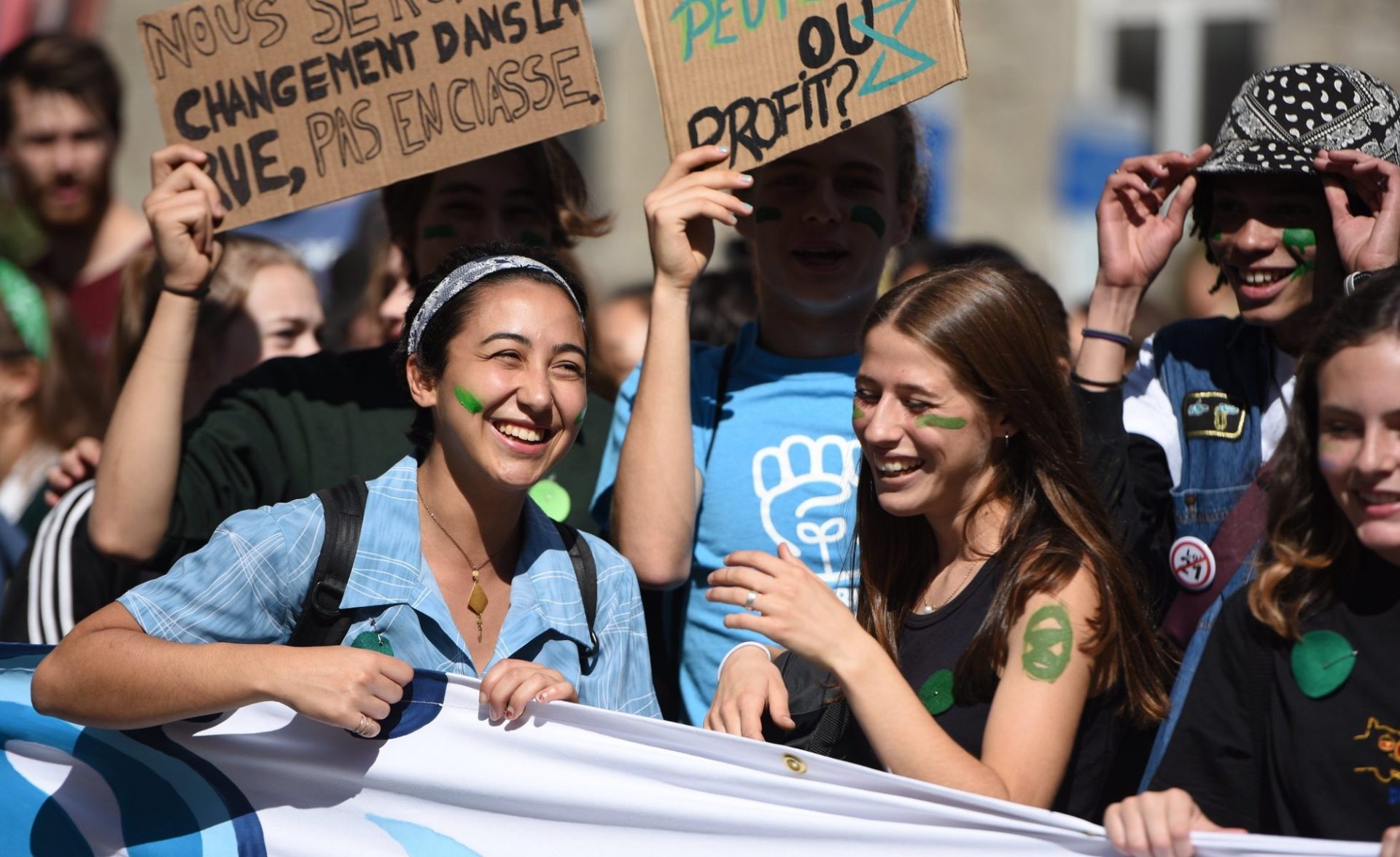 Youth behind smiling behind banner at 2019 youth climate march in Montreal