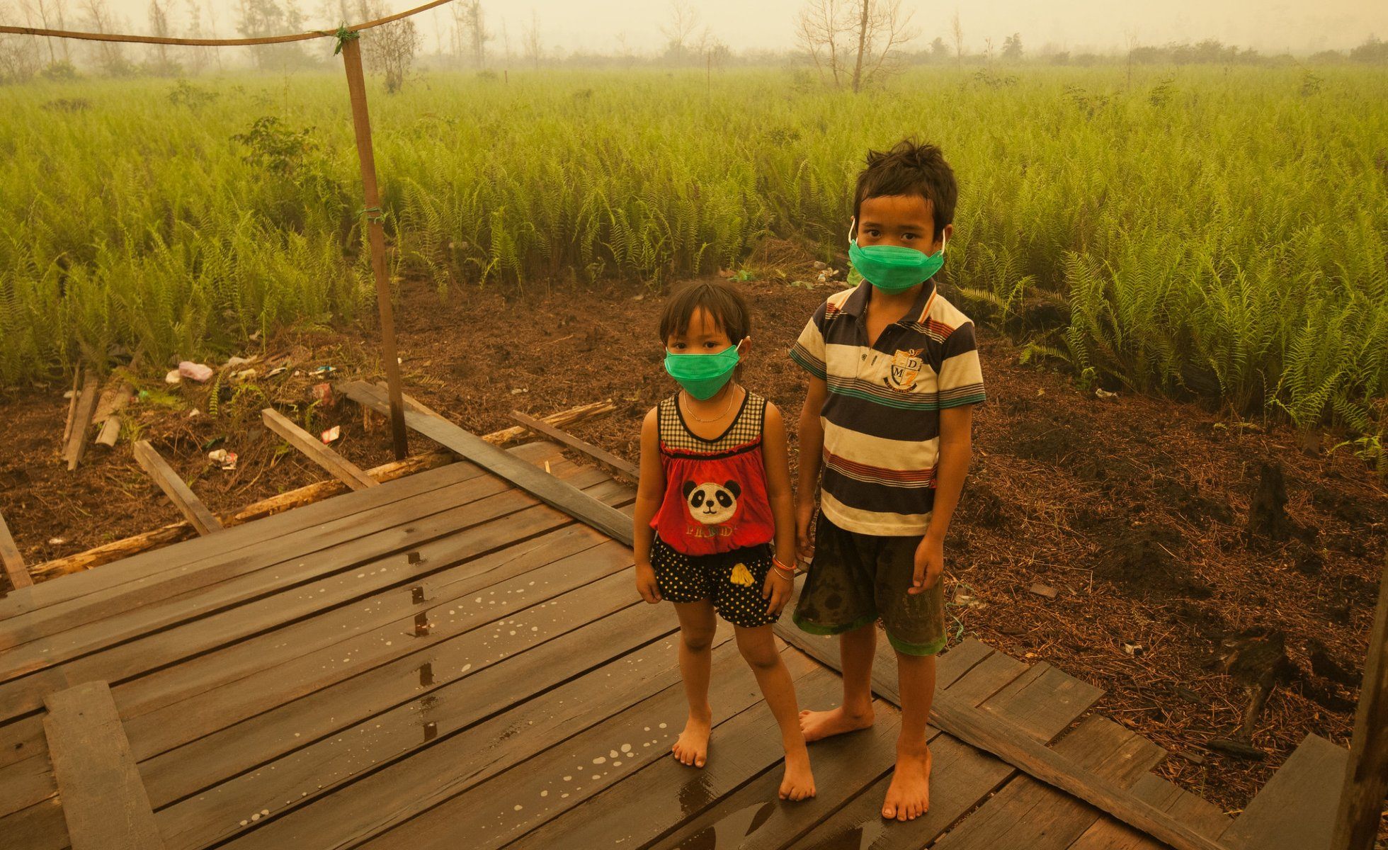 Two children in masks due to pollution from peat farms