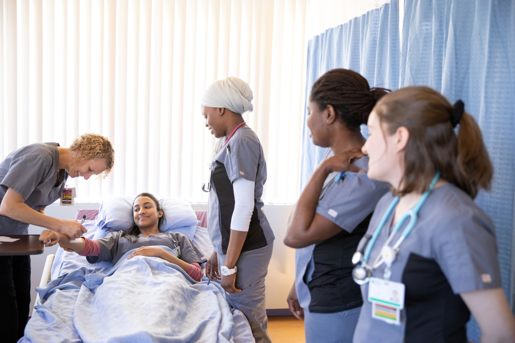 A group of nursing students gathers around a patient.