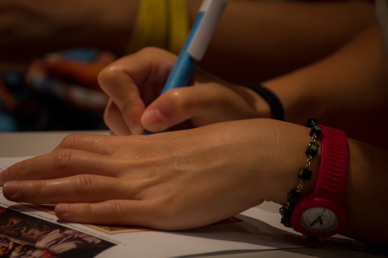 A close-up of a woman's hands holding a pen, writing a card or letter