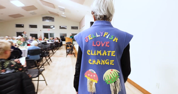 A woman wearing a vest with the words "Jellyfish love climate change" on the back