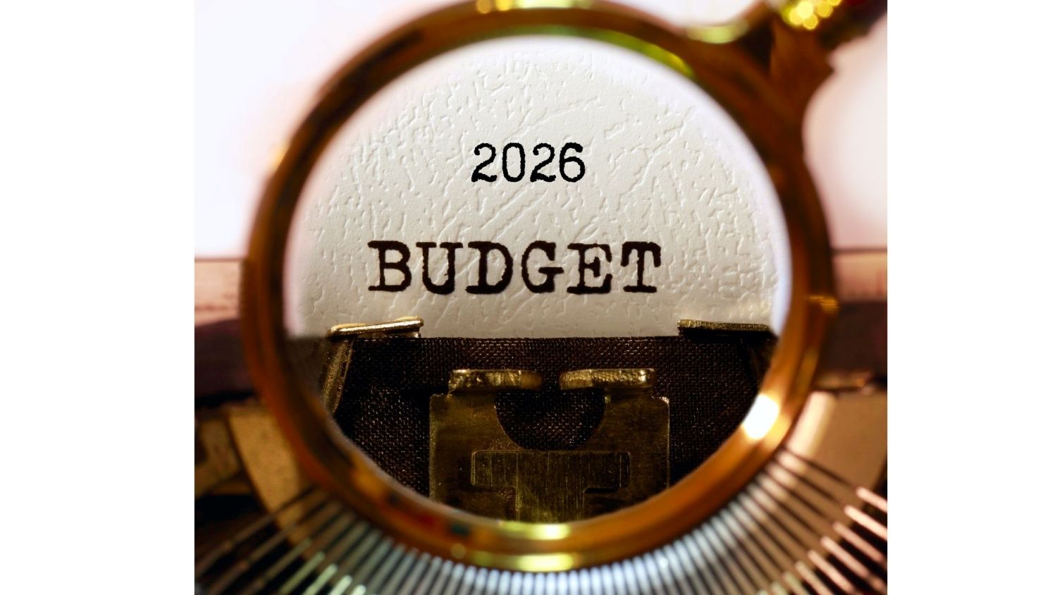 A magnifying glass focused on the printed words "2026 BUDGET"