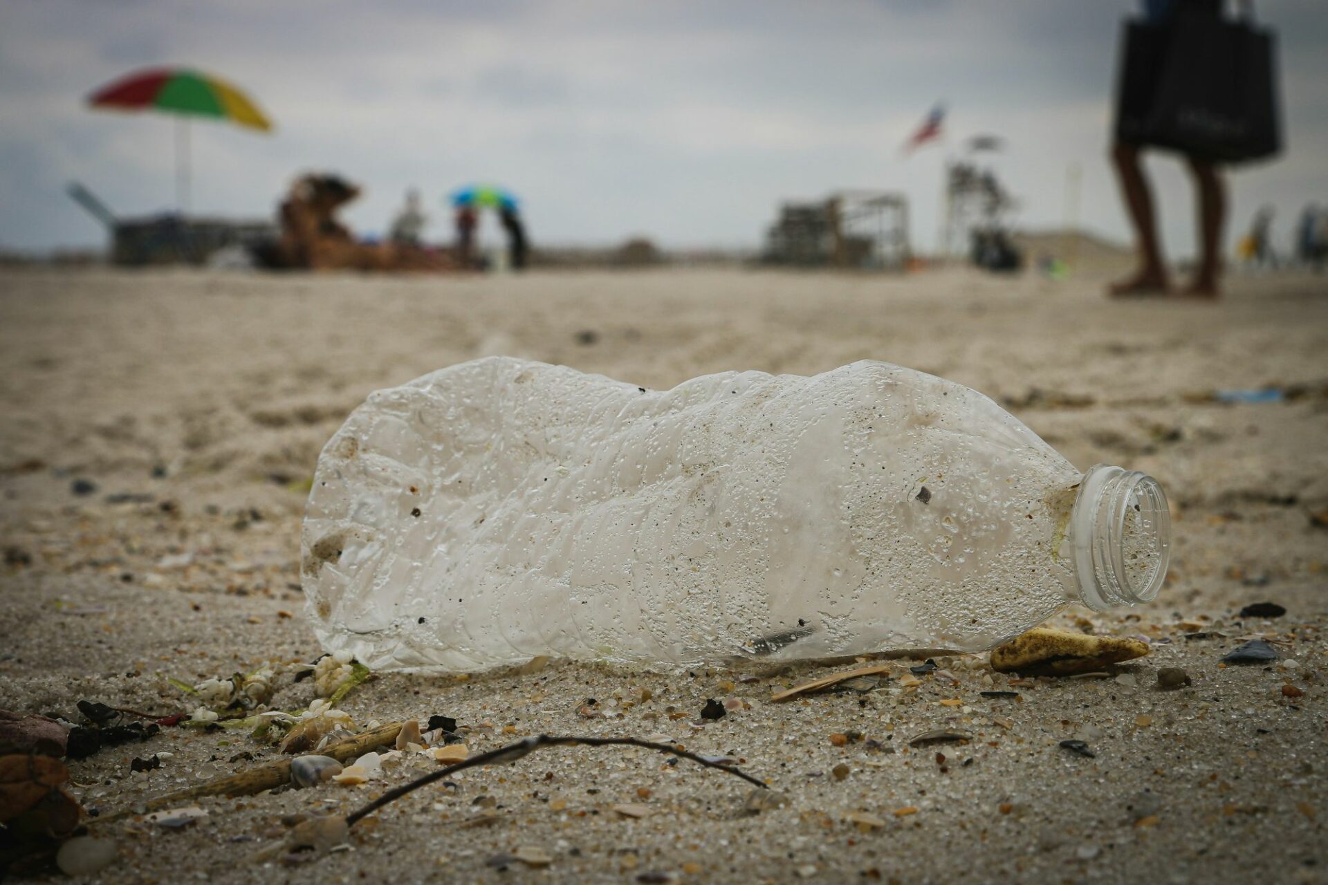 A battered clear plastic water bottle on a sandy beach