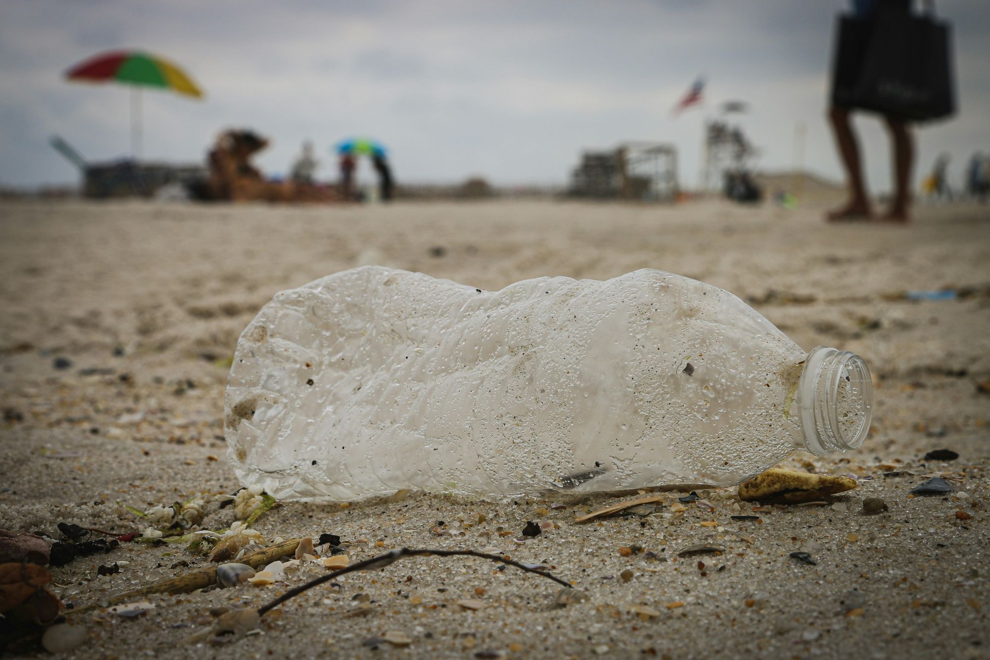A battered clear plastic water bottle on a sandy beach