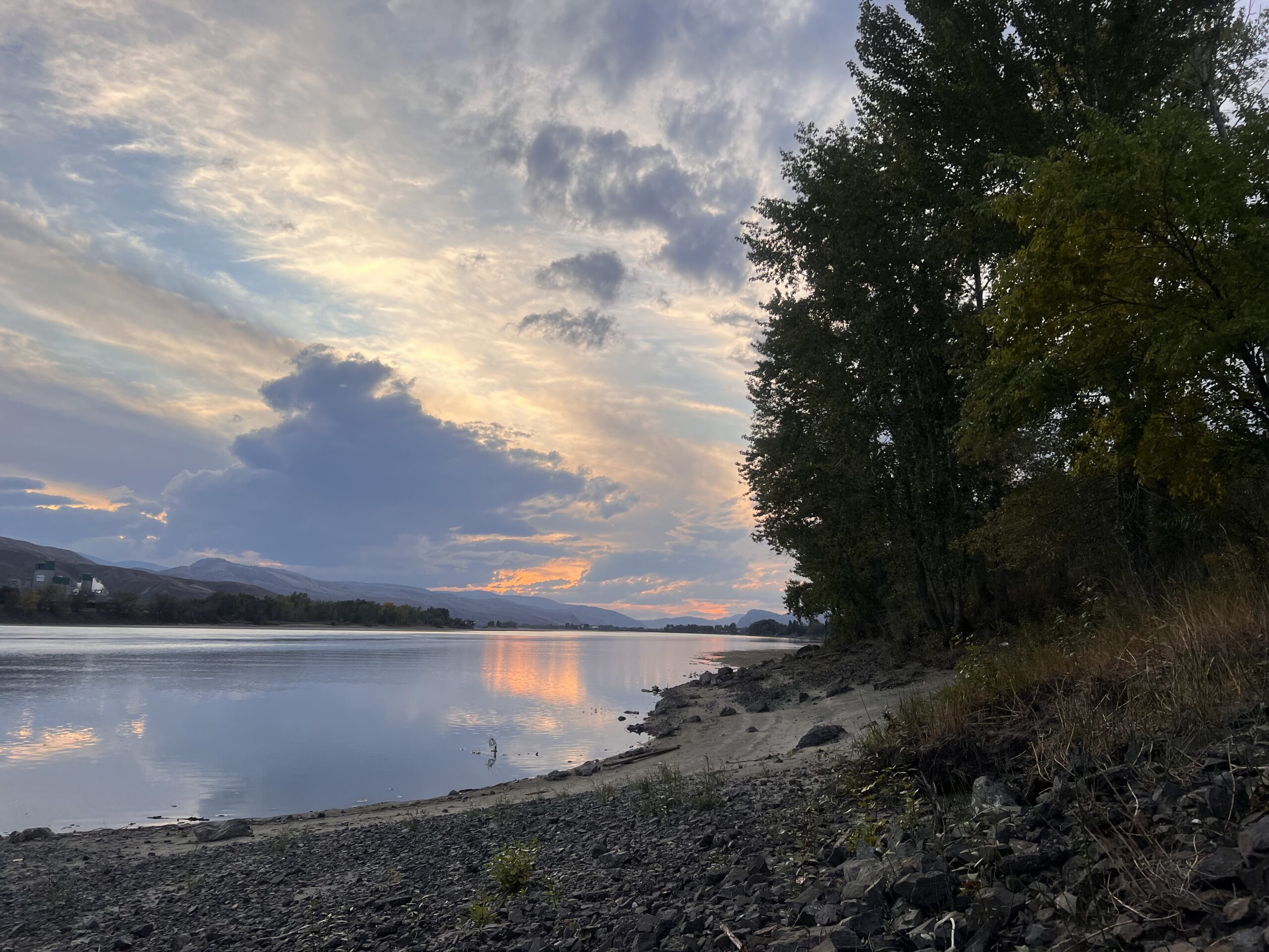Photograph of the Thompson River bank with a sunset in the background